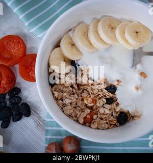 Gesundes Frühstück: Rosinen, getrocknete Aprikosen, Nüsse, Haferflocken, Joghurt und frisches Obst Stockfoto