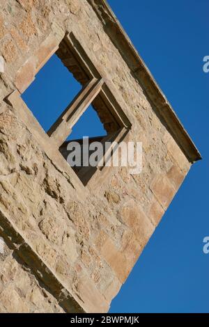 Braunes Fenster in einem Backsteinschloss mit blauem Himmel, abfallend, aber symmetrisch. Deutschland. Stockfoto