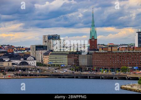 Stockholm, Schweden - 10. August 2017: Blick über den Malaren-See auf traditionelle gotische Gebäude in Normalm und Klara Kirche oder Claire Kirche Stockfoto