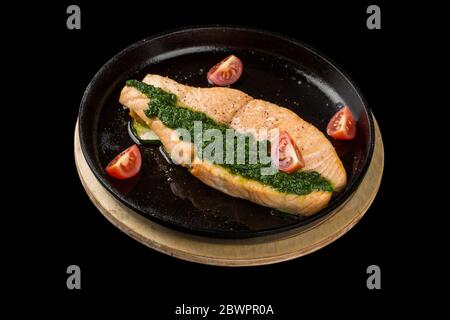 Lachssteak in einer schwarzen Pfanne. Isoliert auf schwarzem Hintergrund. Stockfoto