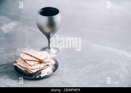 Matzos ungesäuertes Brot mit einer Kiddusch-Tasse Wein. Feiertag der jüdischen Pesah. Banner mit Kopierbereich. Christliches Kommunionkonzept zur Erinnerung an Jesus Stockfoto