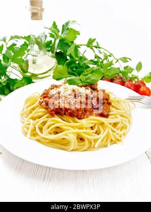Spaghetti-Pasta mit Bolognese-Sauce aus Hackfleisch, Tomatensaft, Knoblauch, Wein und Gewürze mit Käse und Gabel in einem Teller, Pflanzenöl, würziges Kraut Stockfoto
