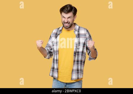 Junger wütender Mann, der seine Hände mit Fäusten hebt. Stockfoto