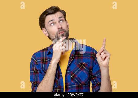Junger dunkelhaariger bärtiger Mann, der in Gedanken steht. Stockfoto