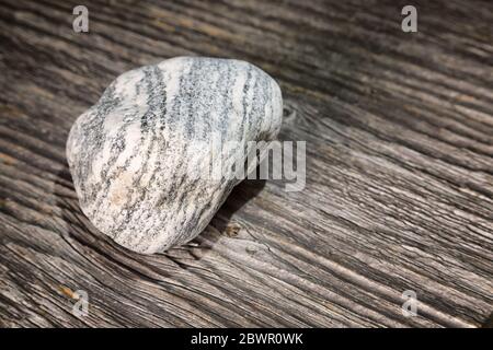 Isolierter Stein mit Streifen auf Holz Stockfoto