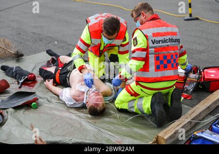 27. Mai 2020, Sachsen, Leipzig: Ein Sanitäter mit "Vorsicht" auf dem Rücken behandelt eine verletzte Person während einer Übung. Während der Übung wurde eine spezielle Tasche für sogenannte "Massenunfall- und Krankheitsfälle" (MANV) vorgestellt. Es enthält unter anderem spezielle Verbandbinden zur Blutungsunterbindung bei schweren äußeren und inneren Verletzungen sowie Markierungen für Menschen mit unterschiedlichem Schweregrad. Bei einem Massenunfall sind zunächst nur wenige Rettungsteams mit einer großen Anzahl von Verletzten konfrontiert. Das Überleben von möglichst vielen Patienten kann durch gewährleistet werden Stockfoto