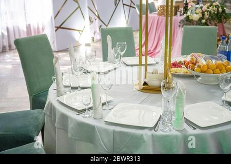 Der Tisch im Restaurant wird zum Abendessen serviert. Auf einem Tisch mit weißer Tischdecke, leeren Weingläsern, Tellern und Servietten. Selektiver Fokus Stockfoto