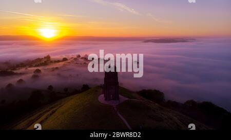 Sonnenaufgang am frühen Morgen über dem Glastonbury Tor und den nebligen Feldern, Somerset. Stockfoto