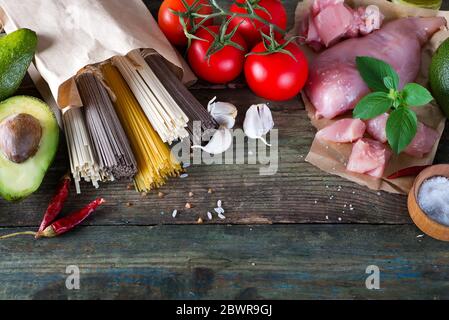 Bündel der Italienische Spaghetti, raw Soba Nudeln und comen, Huhn, rohes Fleisch, Avocado mit Tomaten auf einem alten Holz- Hintergrund, flay legte sich zu kopieren. C Stockfoto