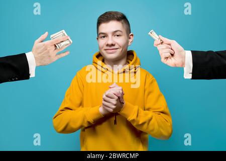 Ein junger Mann in einem hellen Sweatshirt freut sich, dass ein Geschäftsmann gibt ihm Geld Stockfoto