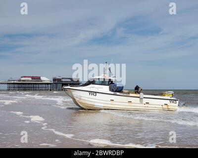 Ein modernes Krabbenboot im Katamaranstil an Land am Cromer Beach, Norfolk wartet darauf, nach einer erfolgreichen Reise mit dem Traktor über die Gezeitenlinie gezogen zu werden. Stockfoto