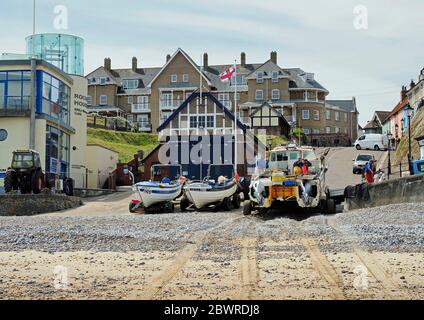 Krabbenboote zogen am Strand unterhalb des Gangway in Cromer, Norfolk mit einem Boot aus, das den Fang des Morgens ausladende. Stockfoto