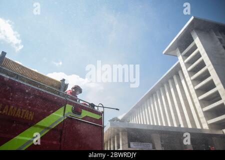 Jakarta, Indonesien. Juni 2020. Ein Feuerwehrmann mit Schutzanzug sprüht Desinfektionsmittel im Komplex der Istiqlal Moschee in Jakarta, Indonesien, 3. Juni 2020. Kredit: Agung Kuncahya B./Xinhua/Alamy Live News Stockfoto