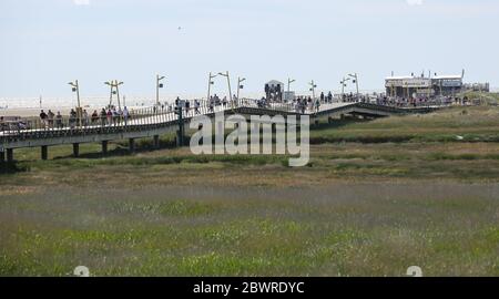 St. Peter Ording, Deutschland. Juni 2020. Urlauber sind auf der Anlegestelle in Sankt Peter-Ording. Der Pier verbindet einen Strandabschnitt mit der Promenade und ist gut einen Kilometer lang. St. Peter-Ording wurde wegen der Koronakrise über Pfingsten einem Verbot von Tagesbesuchern ausgesetzt. Kredit: Bodo Marks/dpa/Alamy Live News Stockfoto