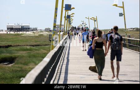 St. Peter Ording, Deutschland. Juni 2020. Urlauber sind auf der Anlegestelle in Sankt Peter-Ording. Der Pier verbindet einen Strandabschnitt mit der Promenade und ist gut einen Kilometer lang. St. Peter-Ording wurde wegen der Koronakrise über Pfingsten einem Verbot von Tagesbesuchern ausgesetzt. Kredit: Bodo Marks/dpa/Alamy Live News Stockfoto