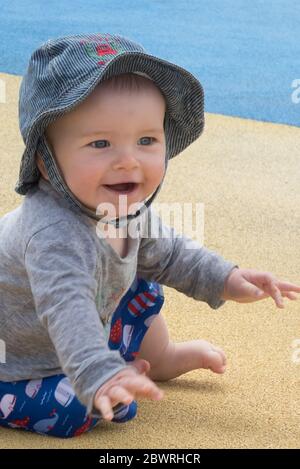 Lachender Junge, 8-9 Monate alt, trägt einen Sonnenhut im Freien in der Sommersonne. MODELL FREIGEGEBEN Stockfoto