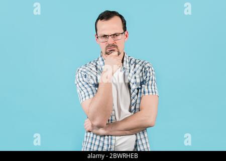 Ein Mann hob seine Augenbrauen und starrt straight, reiben sein Kinn Stockfoto