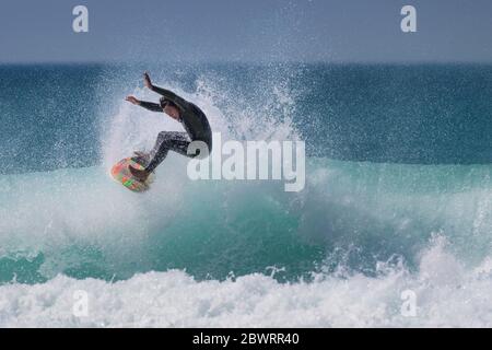 Wilde spektakuläre Action, während ein junger Surfer eine Welle im Fistral in Newquay in Cornwall reitet. Stockfoto