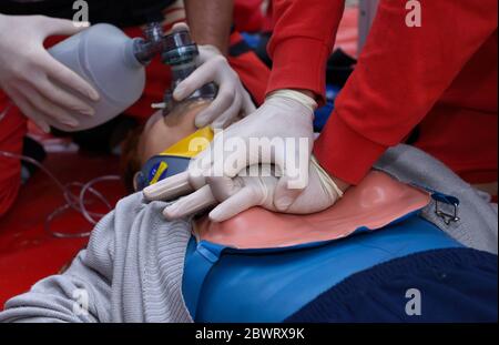 Nothelfer drückt auf die Brust eines Patienten und hält ein Sauerstoffkissen auf seinem Gesicht. Künstliche Beatmung Stockfoto