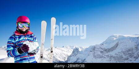 Girl Love Mountain Ski Konzept Halten Sie Schnee in Herzform über schneebedeckten Gipfeln tragen rosa Helm und Farbbrille Stockfoto