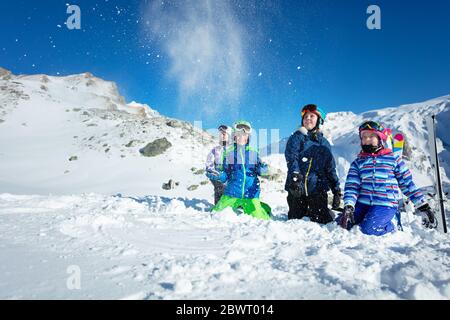 Porträt einer Gruppe von Kindern lag auf dem Boden werfen Schnee in der Luft über schönen Berg Stockfoto