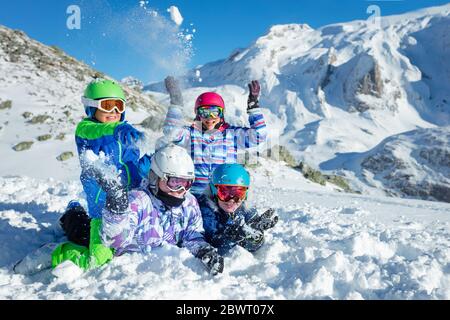 Porträt einer Gruppe von Kindern lag auf dem Boden werfen Schnee in der Luft über schönen Berg Stockfoto