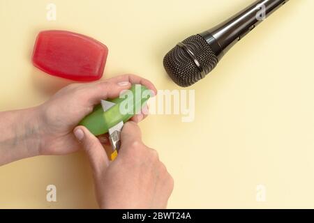 ASMR-Konzept. Spezifische auditive Reizstoffe. Frauenhand schneiden Seife vor dem Mikrofon ab. Draufsicht, flaches Lay. Stockfoto