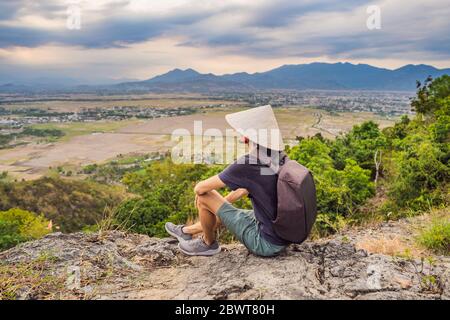 Junger Mann Tourist in einem traditionellen vietnamesischen Hut reist nach Vietnam Stockfoto