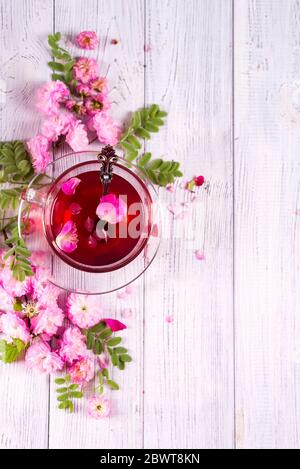 Kräutertee mit Rosen auf weißem Holztisch, von oben gesehen Kopierraum Stockfoto