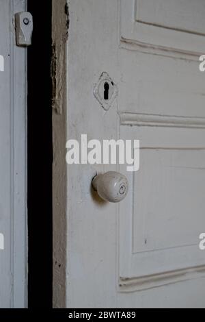 Nahaufnahme einer weiß gestrichenen alten Holztür eines leeren verlassenen alten Gebäudes. Stockfoto