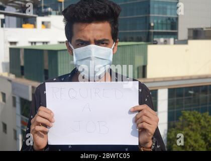 Mann, der medizinische Maske trägt und weißes Papier mit einem Text von halten, erfordern einen Job.Arbeitsloser Mann. Stockfoto