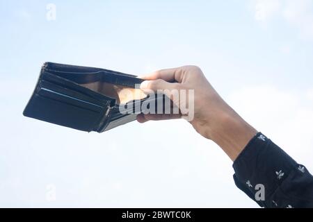 Mann Hand hält schwarze leere Geldbörse isoliert auf Himmel Hintergrund. Stockfoto