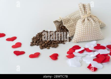 Kaffeebohnen werden aus der Tasche verschüttet. Dekoriert mit dekorativen Herzen. Romantisches Thema, Kaffee mit Liebe machen Stockfoto
