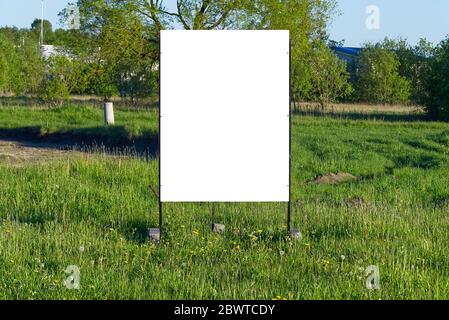 Plakatwand auf einem grünen Hintergrund. Geeignet für Werbung. Leere Plakatwand und Außenwerbung. Mockup Poster draußen. Stockfoto