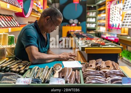 Chongqing, China - August 2019 : älterer chinesischer Mann, der Kamm und andere Haarpflegeprodukte verkauft, CI Qi Kou Altstadt Stockfoto