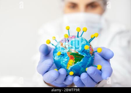 Coronavirus-Pandemie in der Welt hält eine Wissenschaftlerin den Erdglobus in der Hand, der wie ein Coronavirus geformt ist Stockfoto