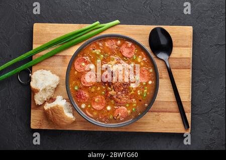 Hähnchen und Wurst Gumbo Suppe in schwarzer Schüssel auf dunklem Schiefer Hintergrund. Gumbo ist louisiana cajun Cuisine Suppe mit Roux. Amerikanische Küche in den USA. Traditionelles E Stockfoto