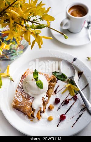 Apfelstrudel mit Puderzucker, Zucker, Mandeln und Vanille-Eis auf weißem Hintergrund Stockfoto