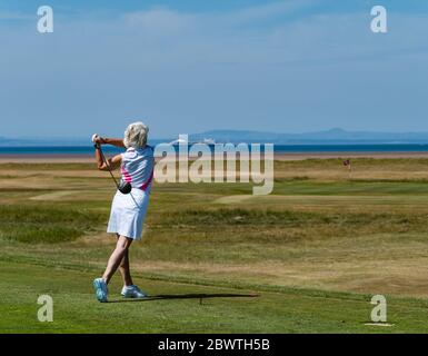 Golferin, die auf dem Golfplatz Golf spielt, mit Blick auf Firth of Forth, East Lothian, Schottland, Großbritannien Stockfoto