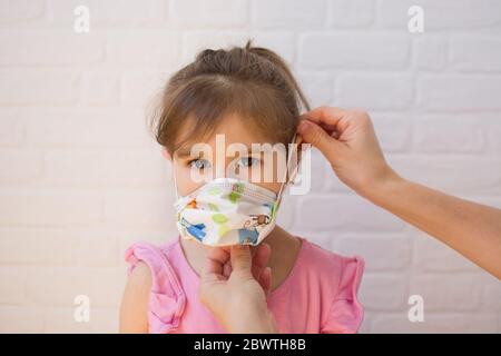 Mutter setzen Schutzmaske pm ihre Tochter. Coronavirus-Konzept. Stockfoto