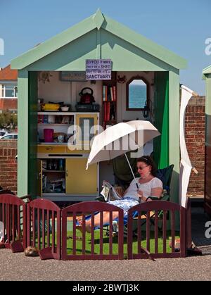 An ihrer Strandhütte in Hove, Brighton, liest eine Frau die Zeitung Stockfoto