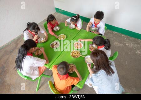 (200603) -- LINGCHUAN, 3. Juni 2020 (Xinhua) -- Lehrer und Schüler essen am 2. Juni 2020 im Mawuzhai Internat im Landkreis Lingchuan, Nordchinesische Provinz Shanxi. Am 2. Juni kehrten Qin Chunlan, Qin Qiulan und Qin Xingwang in die Schule zurück. Früh am Morgen stiegen sie auf das Dreirad ihres Vaters und eilten zur Grundschule des Mawuzhai Internat, das mehr als 10 Kilometer entfernt ist. Die Familie der drei Kinder ist der einzige Haushalt im Dorf Nanbei im Landkreis Lingchuan, und die Grundschule ist die einzige Schule im Umkreis von Dutzenden von Kilometern. Es gibt s Stockfoto