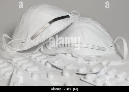 Zwei Gesichtsmasken und ein Stapel von Medikamentenpaketen auf weißem Hintergrund isoliert Stockfoto