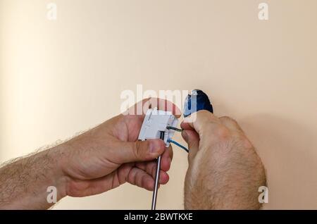 Befestigen der elektrischen Drähte an einem modularen Schalter mit Schraubendreher Stockfoto