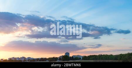 Den schönen Sonnenuntergang über der Bäume und der blaue Himmel gold Sonnenuntergang mit natürlichem Sonnenlicht vor dem Hintergrund der Stadt Häuser und Fabriken Stockfoto