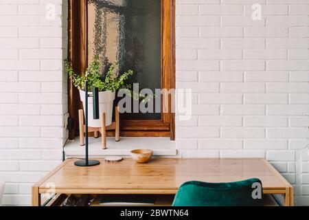Holztisch und Stuhl gegen Zimmerpflanze auf Fensterbank im Home Office Stockfoto