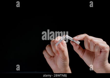 RAUCHVERBOT. Nahaufnahme Frau Hand zerstören Zigaretten auf schwarzem Hintergrund. Welttag Des Tabakkonsums, Mai 31. Speicherplatz für Werbetreibenden kopieren. Stockfoto