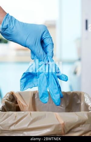 Nahaufnahme eines Mannes, der einen gebrauchten Latexhandschuh in den Mülleimer wirft Stockfoto