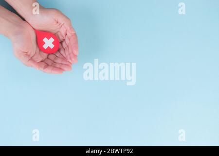 Weltblutspender und Hämophilie-Tag-Konzept. Frauenhände halten einen roten Blutstropfen. Draufsicht mit Kopierbereich. Stockfoto