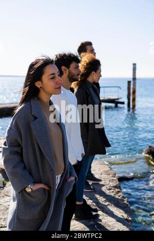 Vier Freunde stehen am Gardasee und blicken auf Italien Stockfoto